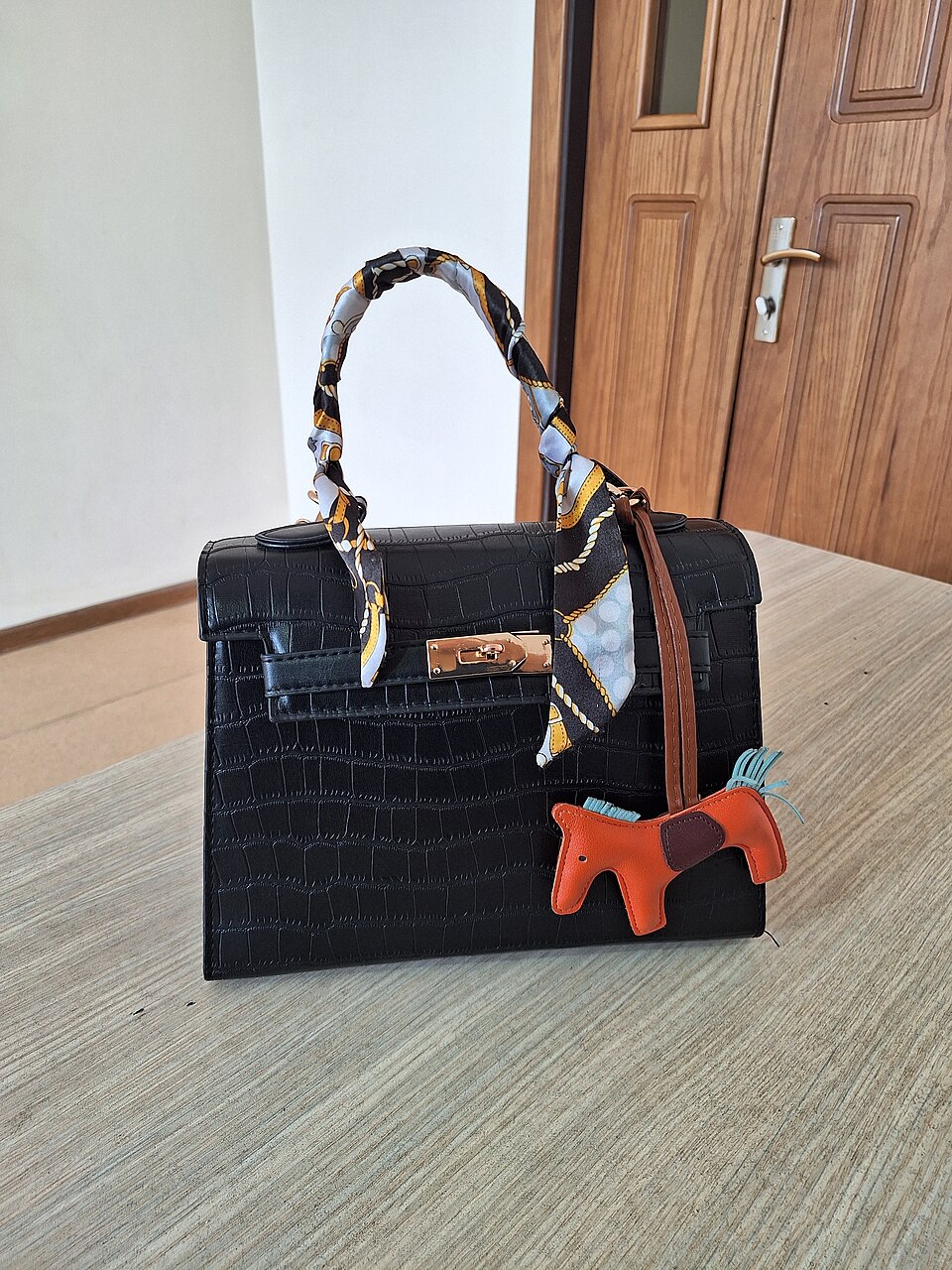 Black handbag indoors beside a wooden door
