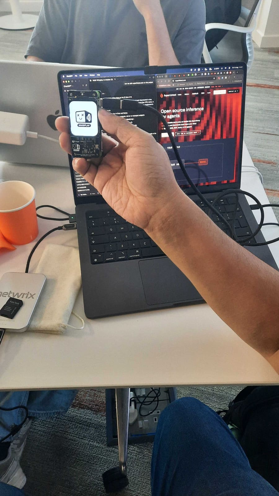 The Aida Relay device running in the palm of a hand next to superlinked.com