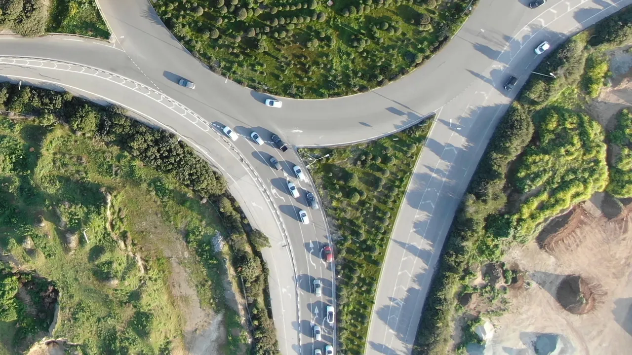 A drone photo of a road junction with queues of cars, with the 20 boxes SAM 3 returned in this part of the photo for car, bus, truck.